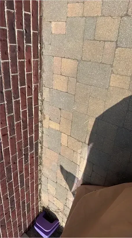 A faded paver landing beside a brick wall, color washed out by sun and weather