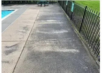 Streaked, stained concrete decking around a community pool