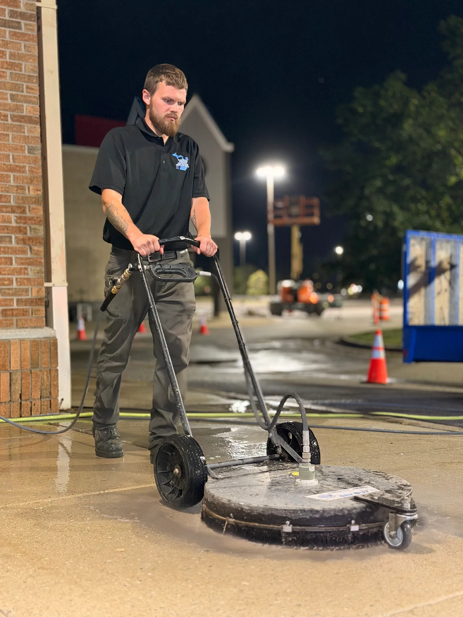 MPWS technician running a rotary surface cleaner across concrete — the square-footage work that drives pricing