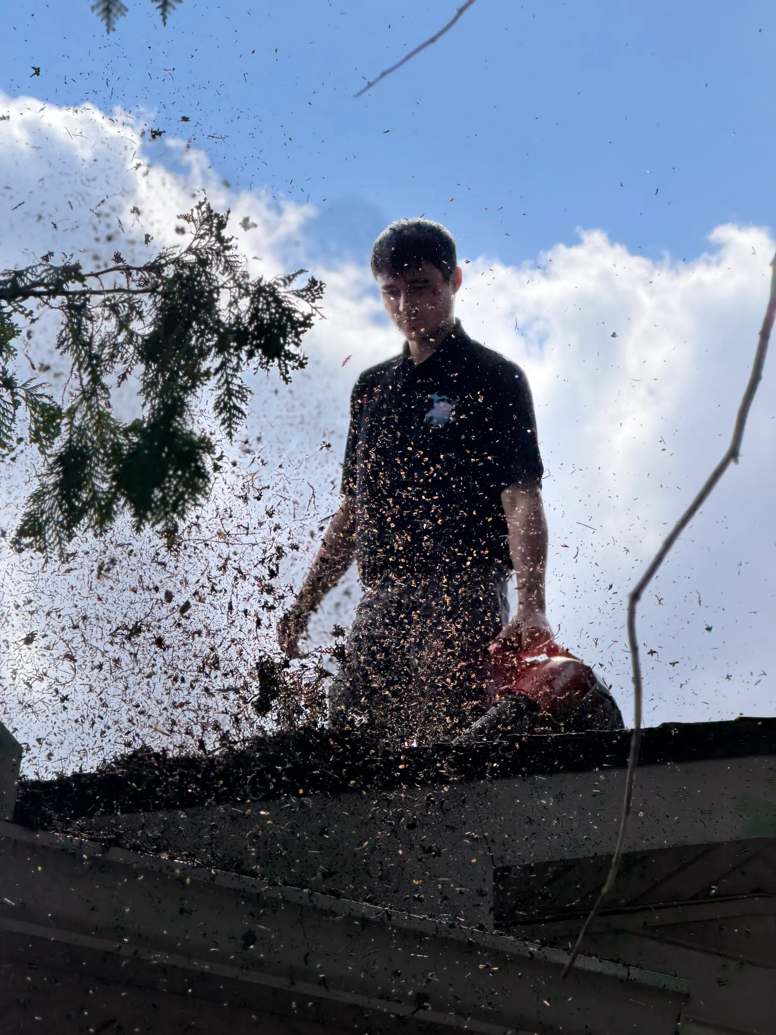 MPWS technician on a roof blowing packed debris out of a gutter run